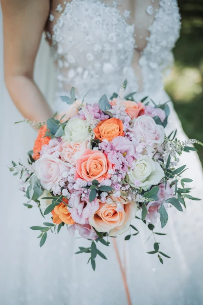 mariée tient son bouquet de mariée contre sa robe en dentelle