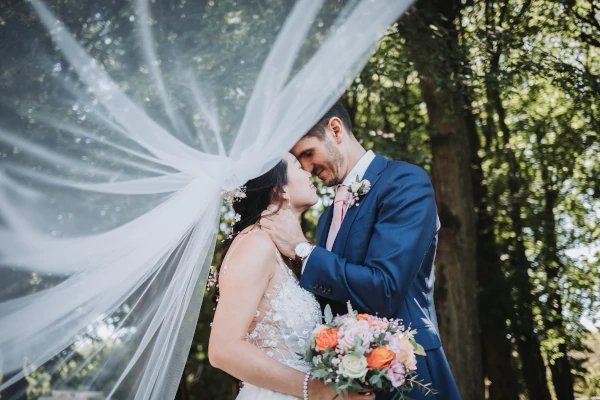 couple s'embrasse sous le voile de la mariée