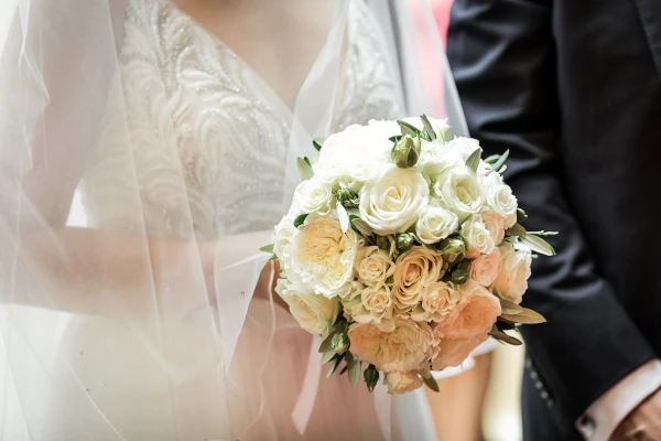 mariée tient un gros bouquet de roses blanches