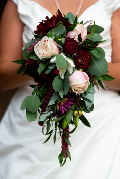 mariée tient son bouquet retombant devant elle