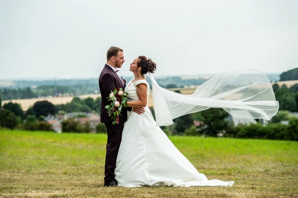 couple face à face dans la campagne avec le voile de la mariée au vent