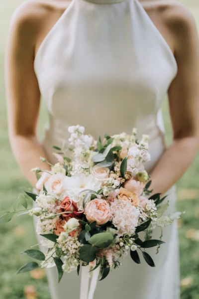 mariée tient son bouquet de mariée devant sa robe