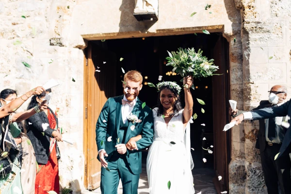 couple sort de l'église sous des confettis de feuillages