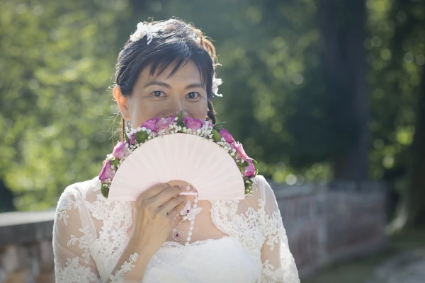 mariée cachée derrière un éventail qui lui sert de bouquet de mariée