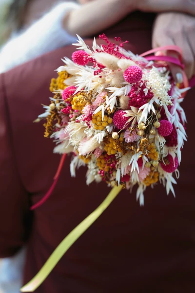 bouquet de fleurs séchées jaunes et roses contre un costume