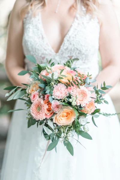 mariée en robe tient son bouquet de mariée devant elle