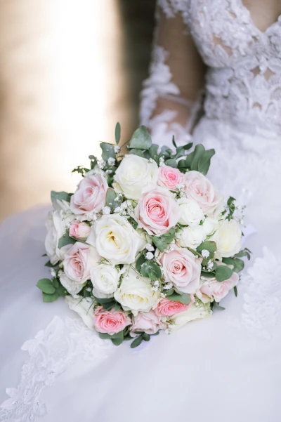 bouquet de mariée en roses posées contre la robe de la mariée