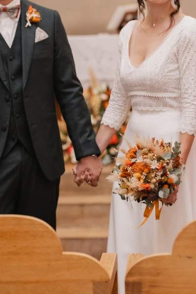 couple de mariés à l'église se tient la main