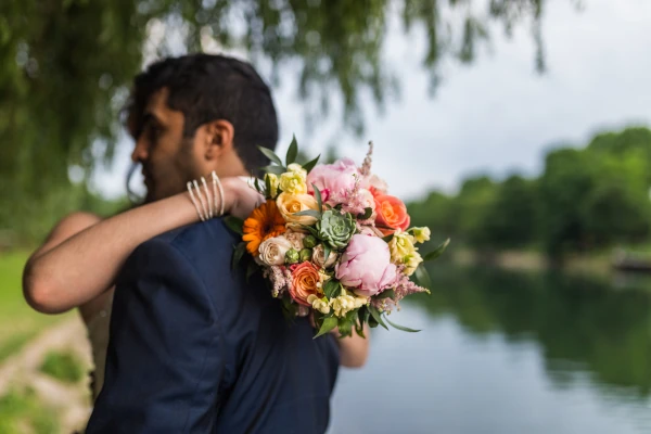 couple enlacé avec le bouquet de mariée contre eux