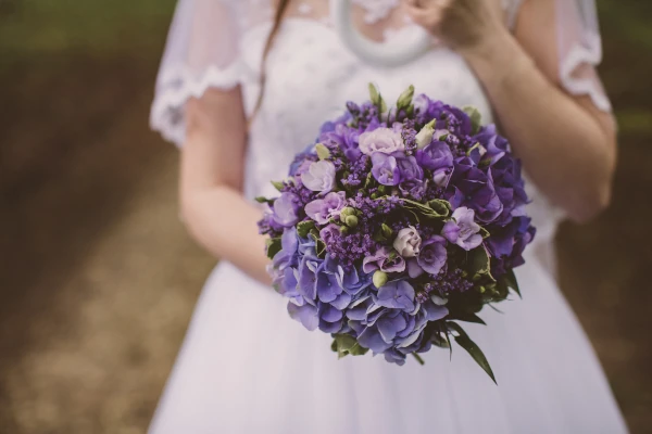 mariée tient devant elle un gros bouquet violet