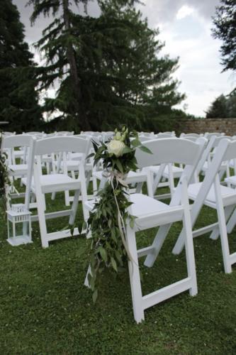 Rose blanche et feuillages sur les chaises de cérémonie aromatique fleuriste mariage