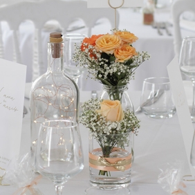 Centre de table doré avec bouteille lumineuse et bocaux fleuris assortis aromatique fleuriste mariage