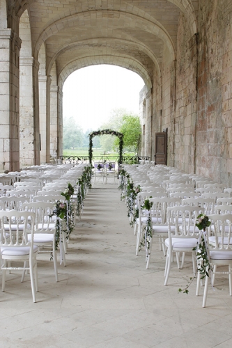 Arche fleurie et bouquet sur les chaises pour l'allée de cérémonie aromatique fleuriste mariage