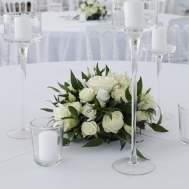 Centre de table en fleurs blanches et feuillages avec photophores et bougies aromatique fleuriste mariage