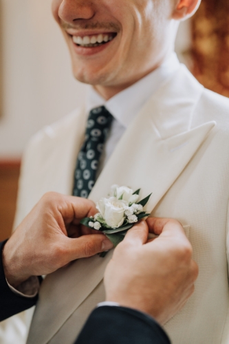 Boutonnière en roses blanches et feuillages