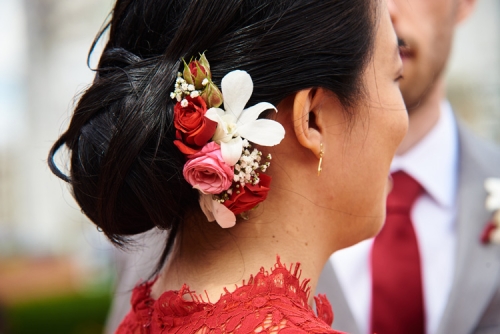 Peigne en fleurs rouges et blanches dans le chignon de la mariée