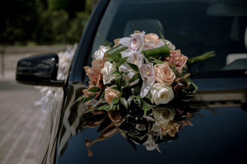 Composition de fleurs pêche et blanche sur capot de voiture