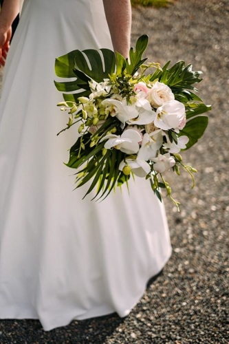 Bouquet de mariée exotique en roses et orchidées avec feuillages tropicaux