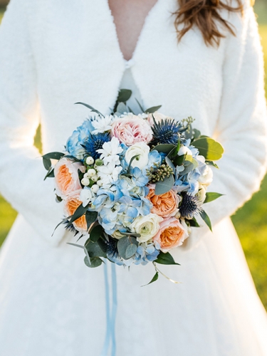Bouquet de mariée bleu et pêche en roses, renoncules et hortensias.