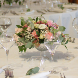 Centre de table en fleurs roses surélevés sur un petit vase en verre